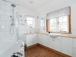 a white bathroom with a shower and a sink at Grange Farm Cottage in Sutton Bridge +33 photos