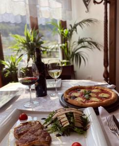 a table with a pizza and two glasses of wine at White House Berat in Berat