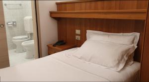 a bedroom with a white bed and a toilet at Hotel Alla Dolina in Sistiana