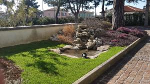 a garden with a small pond in the grass at Hotel Alla Dolina in Sistiana