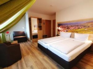 Un dormitorio con una cama grande con un cuadro en la pared. en Gasthof Hotel Weinbau "Zum Goldenen Ochsen", en Sommerhausen 21 fotos más