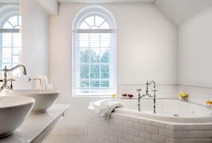 a white bathroom with a tub and two sinks at The Exeter Inn in Exeter +20 photos