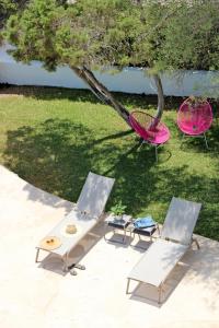 two chairs and a table and a pink chair at Aparthotel Niu d´Aus in Portopetro