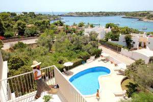 a woman standing on a balcony looking at a swimming pool at Aparthotel Niu d´Aus in Portopetro