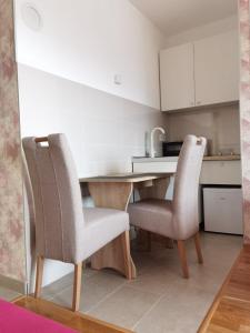 a kitchen with a wooden table and two chairs at Apartman Krasula Doboj in Doboj