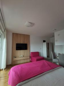 um quarto com uma cama com um cobertor rosa em Apartman Krasula Doboj em Doboj