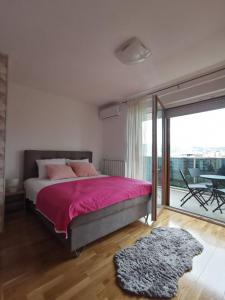 um quarto com uma cama com lençóis cor-de-rosa e uma varanda em Apartman Krasula Doboj em Doboj