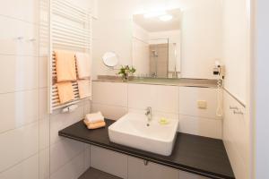een witte badkamer met een wastafel en een spiegel bij PlusNaturHotel direkt am Ederseeufer Waldhotel Wiesemann und Ferienapartments in Waldeck