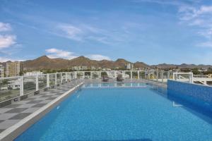 a pool on the roof of a building with mountains in the background at Hotel khumani By Hills N Dunes in Udaipur