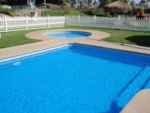 a blue swimming pool with a white fence at Cabañas Punto Verde in La Serena