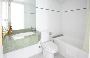 a white bathroom with a toilet and a sink at Aparthotel Niu d´Aus in Portopetro
