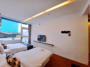 a room with two beds and a tv on the wall at Hiinn B&B in Hualien City