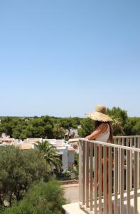 a woman in a straw hat sitting on a balcony at Aparthotel Niu d´Aus in Portopetro