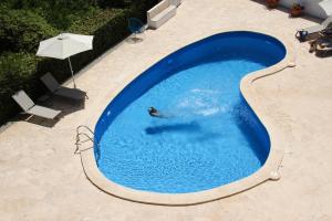 a person swimming in a large blue swimming pool at Aparthotel Niu d´Aus in Portopetro