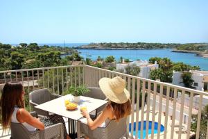 two women sitting at a table on a balcony at Aparthotel Niu d´Aus in Portopetro