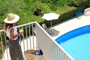 a woman in a hat standing next to a pool at Aparthotel Niu d´Aus in Portopetro