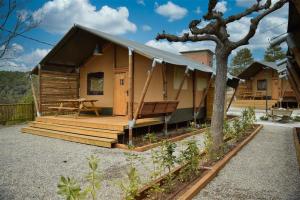 Cabaña de madera con porche y árbol en Camping La Ribera Salada, en 