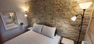 a bedroom with a bed with a stone wall at ApartHotel SAVAS 3 Studio and parking in Kaunas