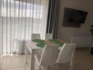 a dining room table with white chairs and a television at Apartament na Klifowej in Niechorze