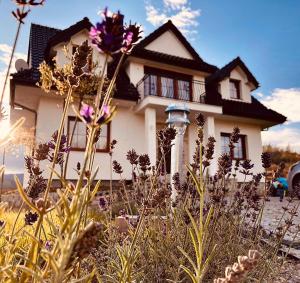 una casa con flores púrpuras delante de ella en Lawendowy Dworek, en Laskówka