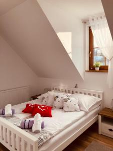 1 dormitorio con cama blanca y almohadas rojas en Lawendowy Dworek, en Laskówka