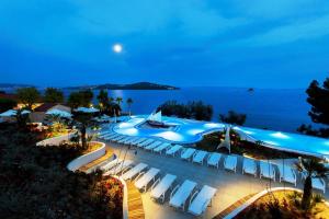 - une piscine à débordement avec des chaises et l'océan la nuit dans l'établissement Salve Croatia Mobile Homes in Amadria Park Trogir, à Seget Vranjica