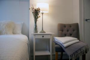 um quarto com uma cama e uma cadeira com um vaso de flores em Downshire Haven em Holywood