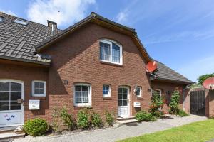 ein rotes Backsteinhaus mit einer weißen Tür in der Unterkunft Ferienhaus Grodehus in Dornumergrode