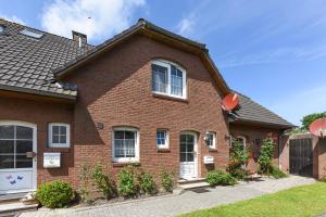 una casa de ladrillo rojo con puerta blanca en Ferienhaus Grodehus, en Dornumergrode