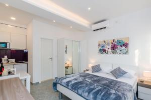 a white bedroom with a bed and a kitchen at Apartments L&M in Dubrovnik