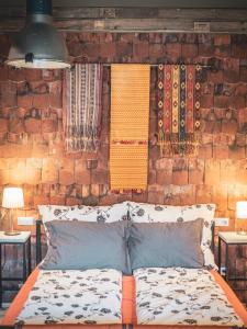 uma cama num quarto com uma parede de tijolos em Hungry Grape Guests em Erdobénye