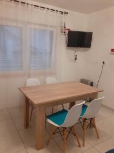 a dining room table with white chairs and a flat screen tv at Apartment Marinero in Šibenik