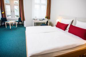 a bedroom with a large white bed with red pillows at Erbacher Hof, Bistum Mainz in Mainz