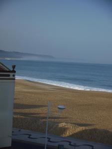 a view of a beach with a building and the ocean at Bed & Seaside in Nazaré
