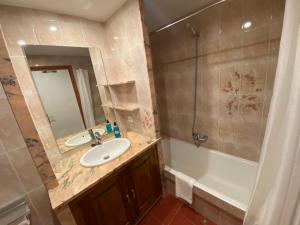 een badkamer met een wastafel, een bad en een spiegel bij El Puente in Boltaña