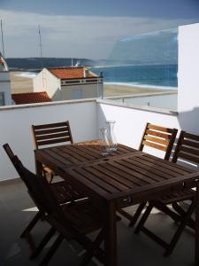 un tavolo in legno con sedie e un balcone con vista sull'oceano. di Bed & Seaside a Nazaré