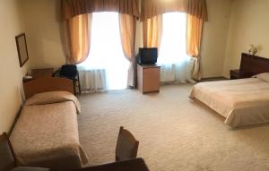 a hotel room with two beds and a television at Готель Ягодин in Starovoitove
