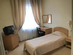 a bedroom with a bed and a desk and a television at Готель Ягодин in Starovoitove