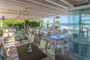 a restaurant with tables and chairs and the beach at Princess Irini Sea Front ApartHotel in Rethymno