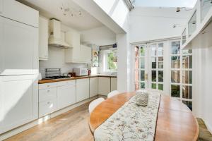 eine Küche mit einem Holztisch und weißen Schränken in der Unterkunft Characterful & Cosy Jericho House (sleeps up to 8) in Oxford