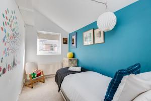 a blue bedroom with a bed and a chair at Characterful & Cosy Jericho House (sleeps up to 8) in Oxford