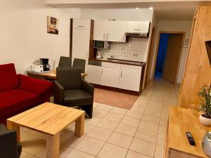 ein Wohnzimmer mit einem roten Sofa und einer Küche in der Unterkunft Ferienwohnungen Weitblick & Am Speicher in Wiek auf Rügen 