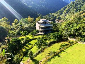 ein Gebäude inmitten eines Feldes mit Bäumen in der Unterkunft Sla Ulay Backpacker Hostel in Wulai