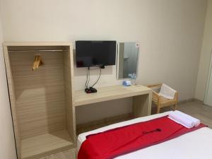 1 dormitorio con escritorio, TV y cama en RedDoorz near Alun Alun Purbalingga, en Purbolinggo