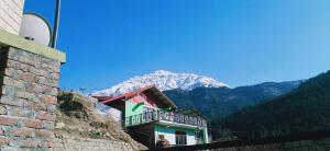 a building with a snow covered mountain in the background at Mahima in Sāngla