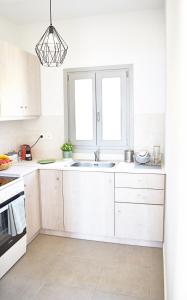 a white kitchen with a sink and a window at Antigoni Villas in Gavrio