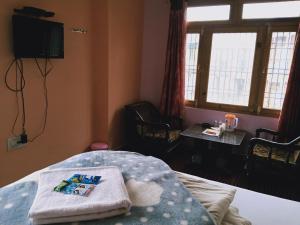 a room with a bed and a table and windows at Mahima in Sāngla