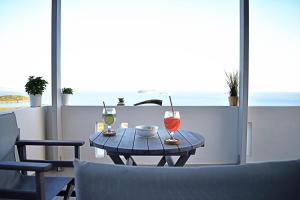 a table with two glasses of wine on a balcony at Antigoni Villas in Gavrio