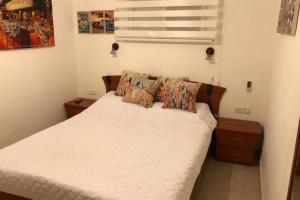 a bedroom with a bed with white sheets and pillows at דירת נופש - עין כרם in ‘En Kerem