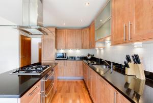 una cocina con armarios de madera y electrodomésticos de acero inoxidable en Britannia Penthouse, en Edimburgo
